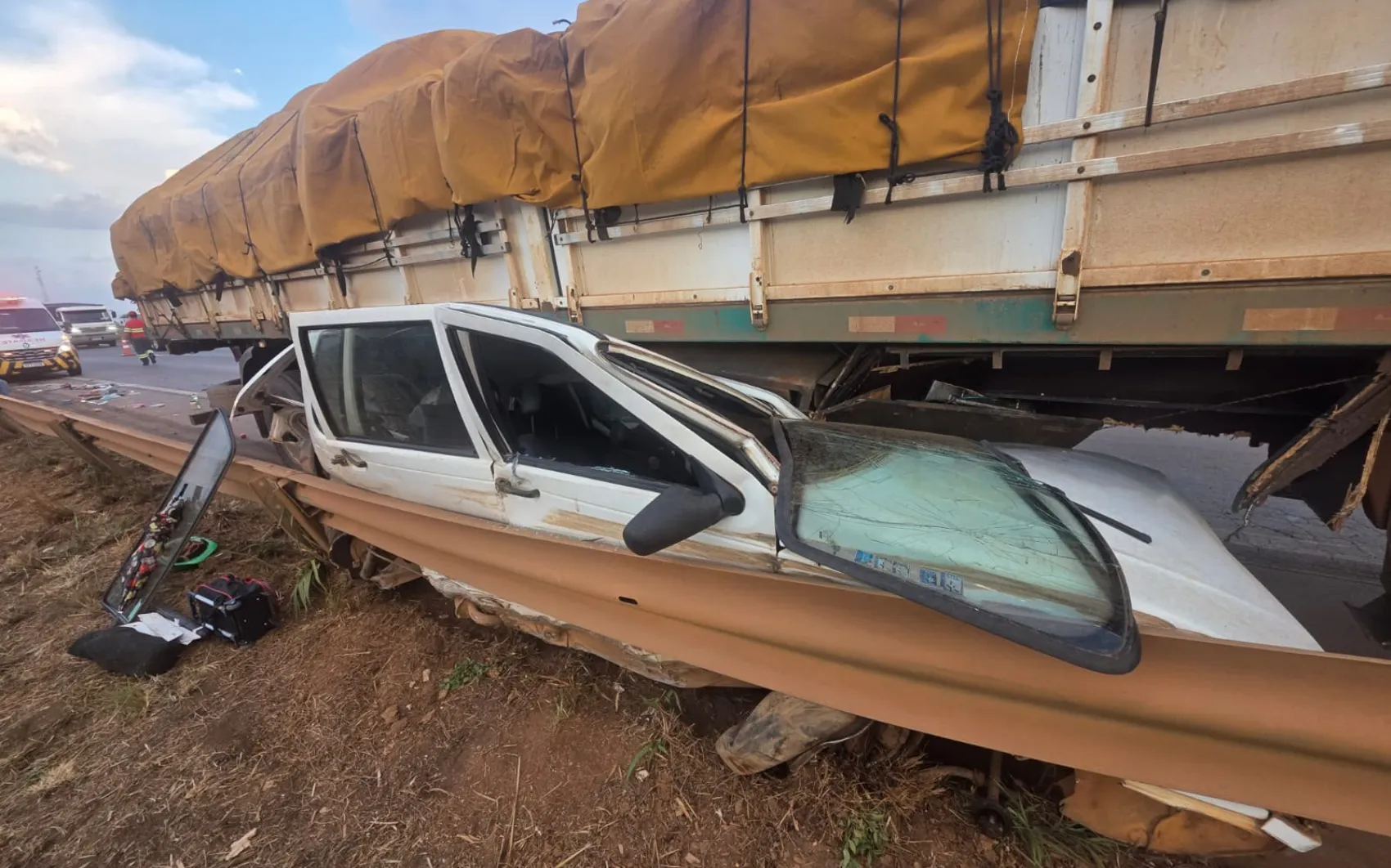 Carro fica espremido embaixo de  caminhão, mas ocupantes saem ilesos; imagem impressionante